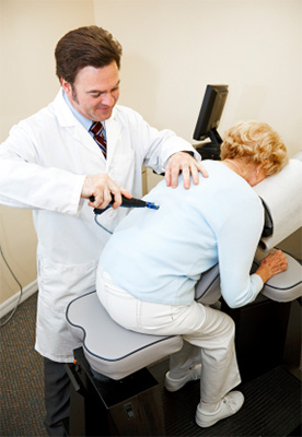 Chiropractor adjusting patient with activator instrument